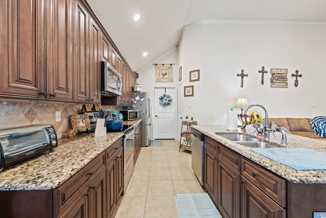 kitchen with appliances with stainless steel finishes, lofted ceiling, backsplash, crown molding, and light stone countertops