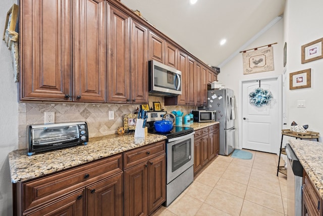 kitchen featuring backsplash, stainless steel appliances, vaulted ceiling, and light stone counters