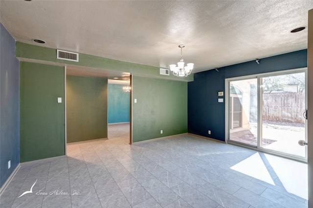 spare room with an inviting chandelier, a textured ceiling, and light tile floors