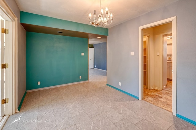 empty room featuring light tile flooring and a chandelier