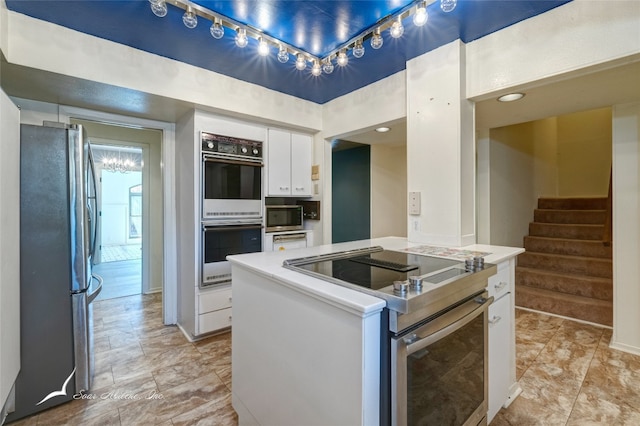 kitchen with a notable chandelier, light tile flooring, appliances with stainless steel finishes, white cabinets, and track lighting