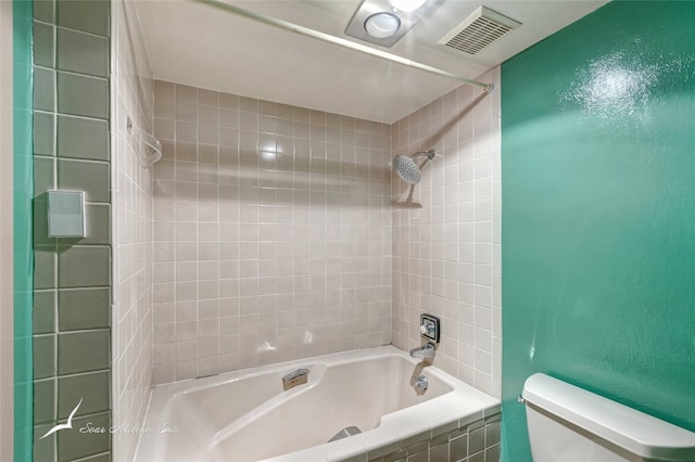 bathroom with tiled shower / bath combo and toilet