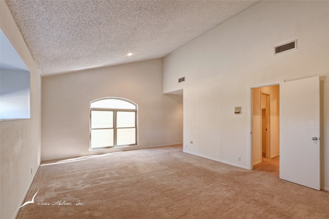 empty room with light carpet, high vaulted ceiling, and a textured ceiling