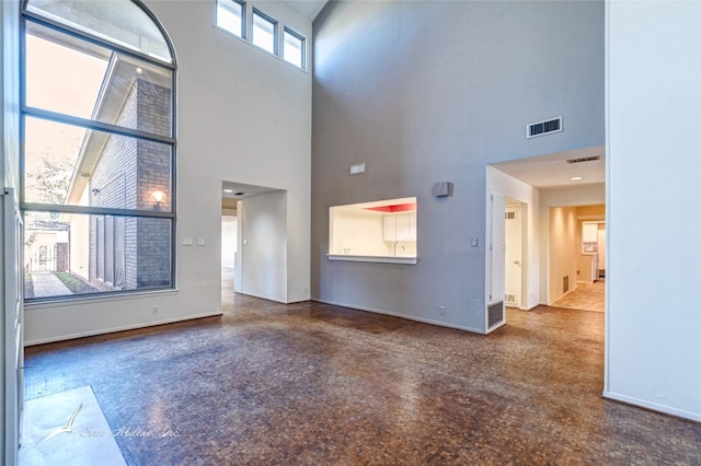 unfurnished living room with a towering ceiling and a wealth of natural light