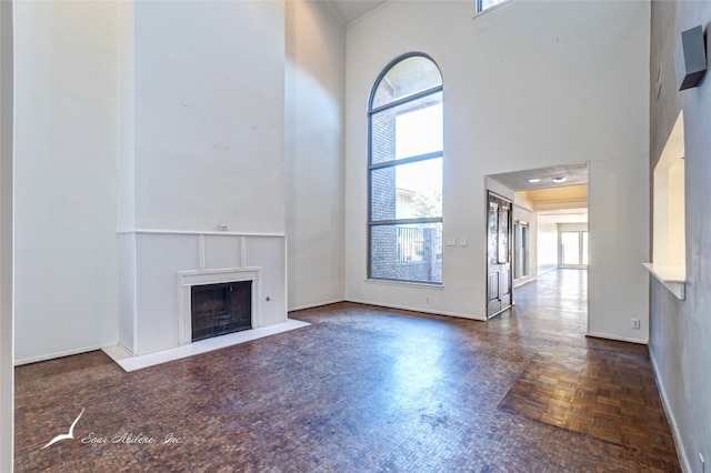 unfurnished living room with a high ceiling and dark parquet floors