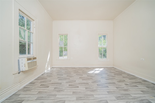 empty room featuring crown molding, light wood-type flooring, and plenty of natural light