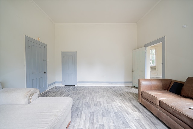 living room with light wood-type flooring, ornamental molding, and a towering ceiling