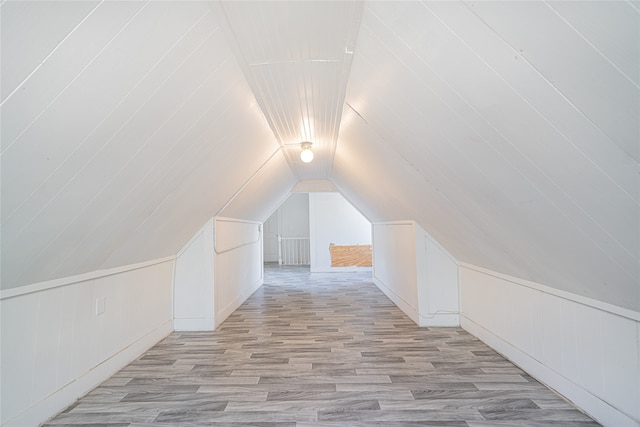 bonus room featuring wood walls, light hardwood / wood-style floors, and vaulted ceiling