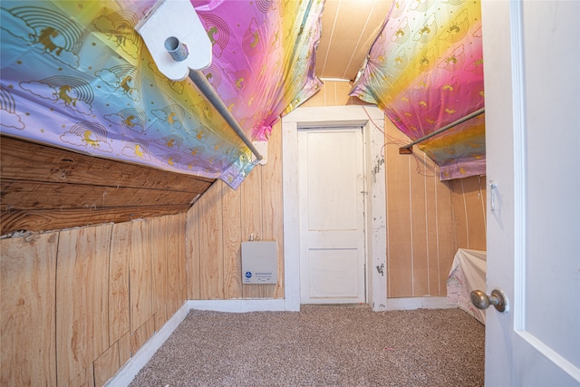 additional living space featuring carpet flooring, vaulted ceiling, and wood walls