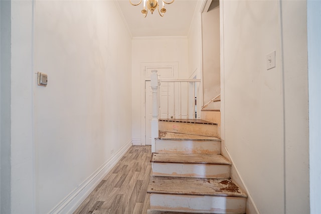 stairway featuring crown molding, a chandelier, and hardwood / wood-style floors