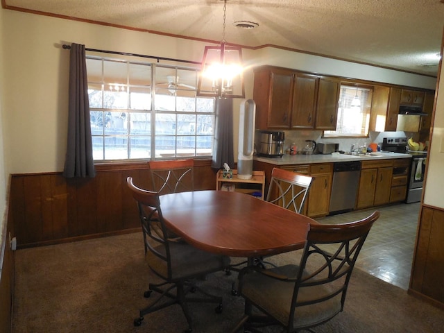 dining area with a wealth of natural light, a textured ceiling, and wood walls