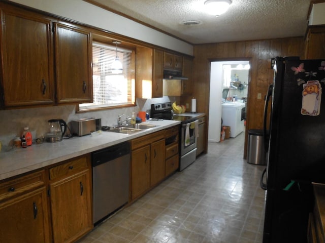 kitchen featuring stainless steel appliances, washing machine and dryer, sink, and a textured ceiling