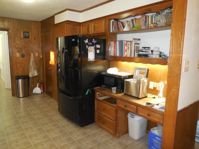 kitchen with black fridge, wooden walls, and a textured ceiling