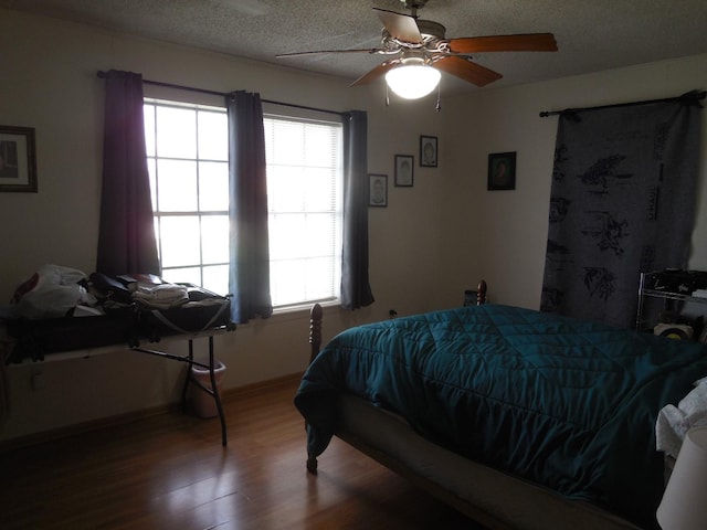 bedroom featuring hardwood / wood-style flooring, ceiling fan, multiple windows, and a textured ceiling