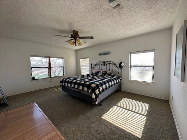 carpeted bedroom featuring ceiling fan and a textured ceiling