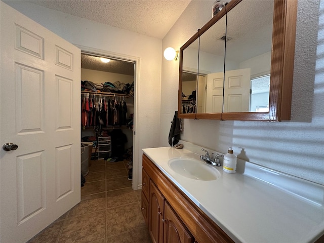 bathroom with a textured ceiling, tile flooring, and large vanity