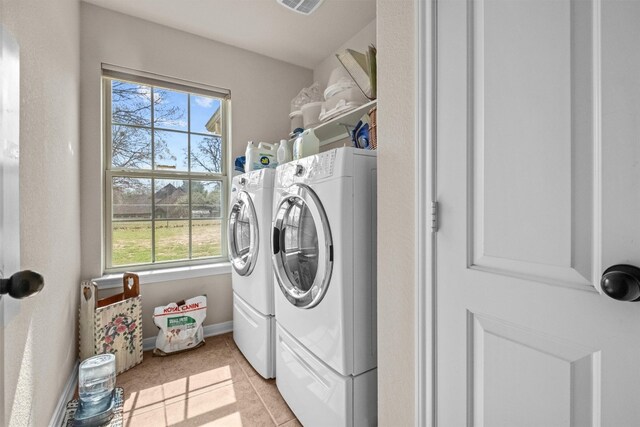 clothes washing area with washer and dryer and light tile floors