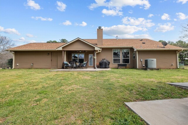 rear view of house with a patio, central air condition unit, and a yard