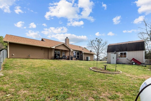 rear view of property with a lawn and an outdoor structure