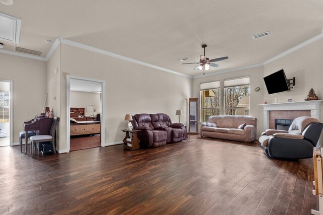 living room with dark hardwood / wood-style flooring, ceiling fan, crown molding, and a tiled fireplace