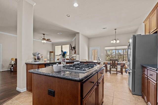 kitchen with light tile floors, hanging light fixtures, ceiling fan with notable chandelier, and stainless steel appliances