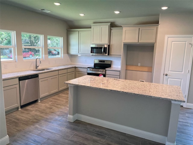 kitchen with stainless steel appliances, dark hardwood / wood-style floors, light stone countertops, and sink