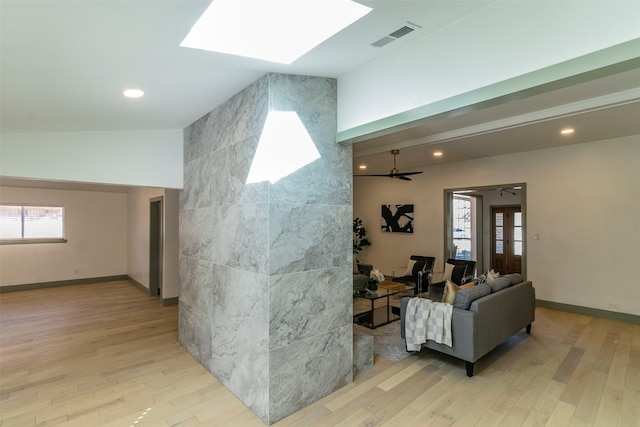 interior space featuring a skylight, ceiling fan, and light wood-type flooring