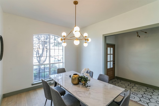 dining area featuring light wood-type flooring, plenty of natural light, and a chandelier