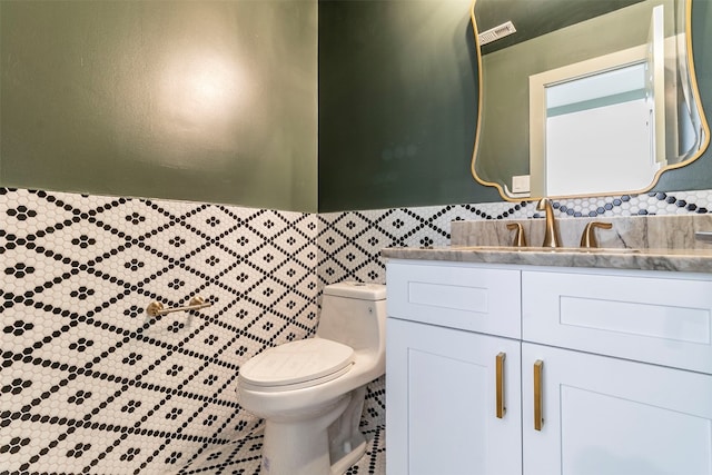 bathroom with tile walls, toilet, and large vanity