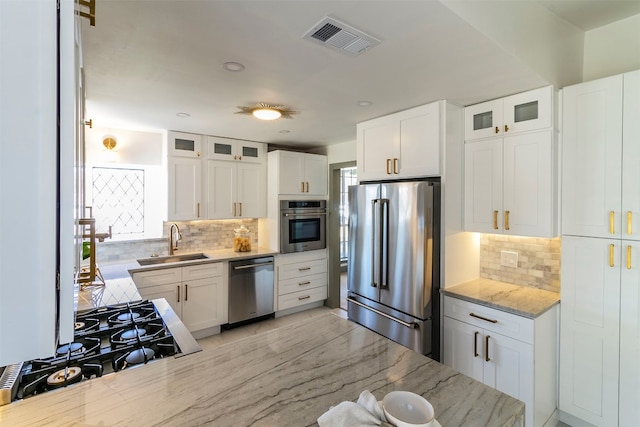 kitchen with backsplash, stainless steel appliances, white cabinetry, and sink