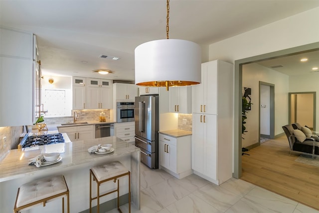 kitchen with pendant lighting, a breakfast bar, stainless steel appliances, backsplash, and white cabinetry