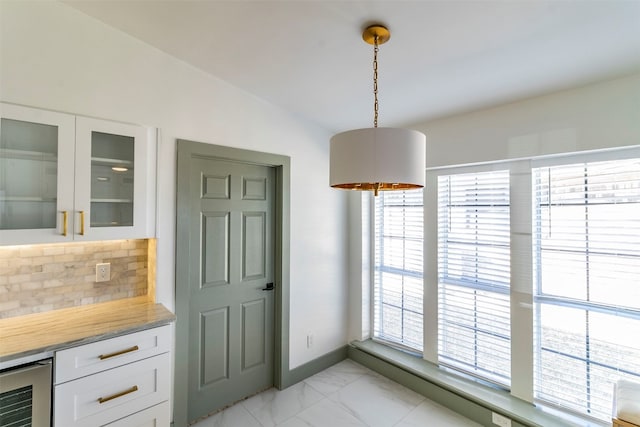 dining space featuring light tile floors, wine cooler, and vaulted ceiling