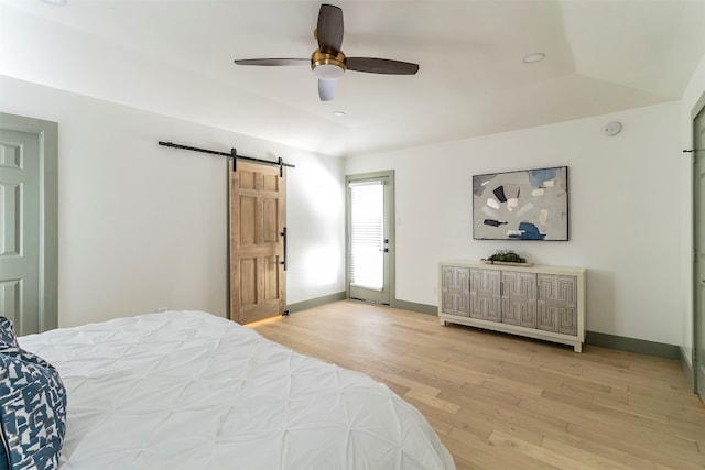 bedroom featuring a barn door, ceiling fan, and light hardwood / wood-style floors