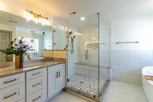 bathroom with separate shower and tub, tile floors, and vanity with extensive cabinet space