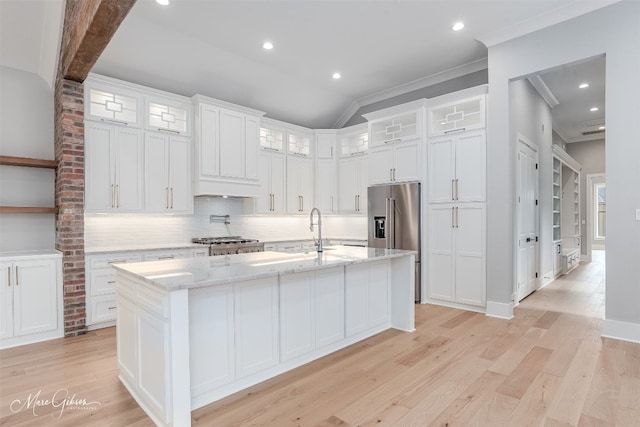 kitchen featuring brick wall, an island with sink, vaulted ceiling, white cabinetry, and light wood-type flooring