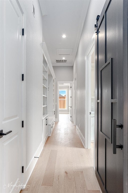 hall featuring light wood-type flooring and a barn door