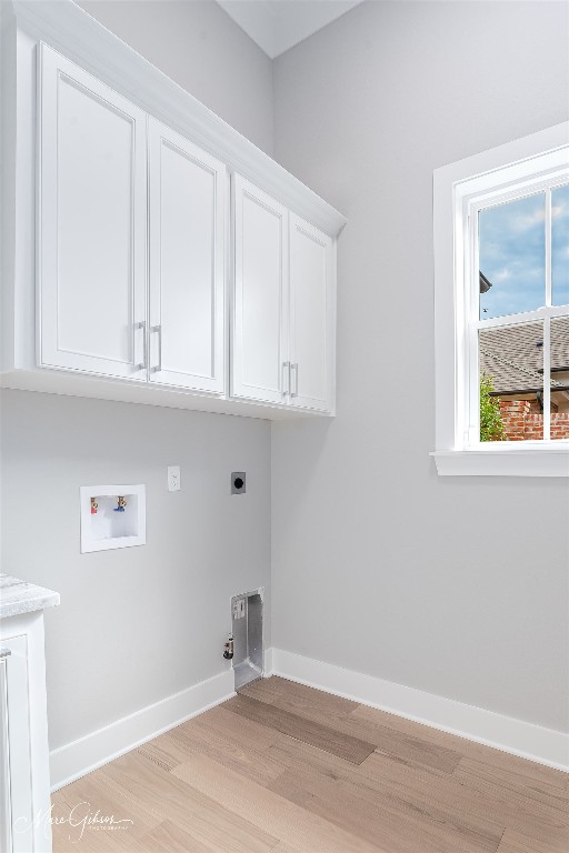 laundry room featuring gas dryer hookup, hookup for an electric dryer, cabinets, hookup for a washing machine, and light hardwood / wood-style flooring