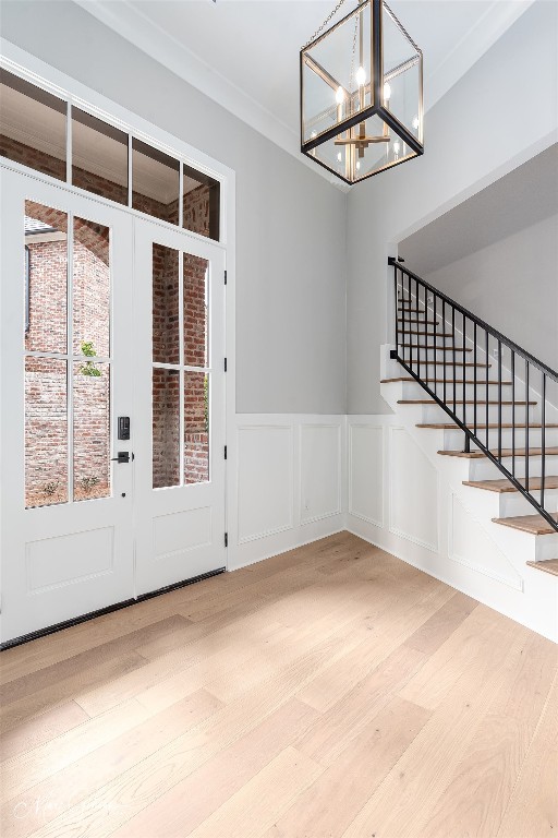 interior space featuring a chandelier, light hardwood / wood-style floors, french doors, and crown molding