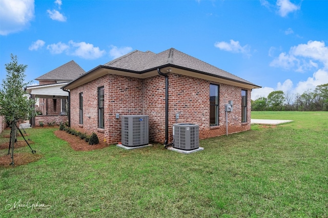 back of property featuring central air condition unit and a yard