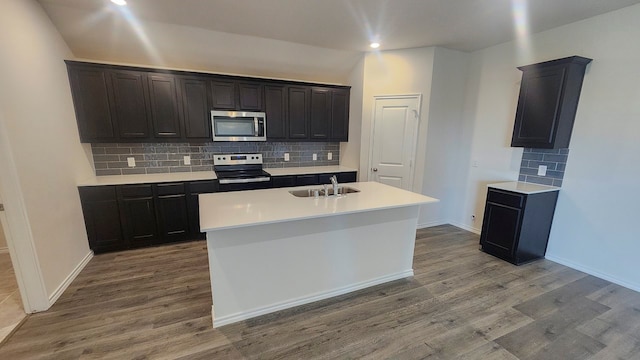 kitchen featuring backsplash, stainless steel appliances, hardwood / wood-style floors, sink, and a kitchen island with sink