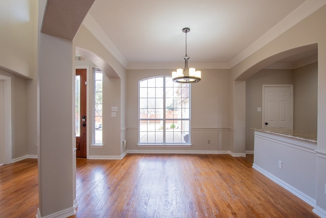 foyer with an inviting chandelier, crown molding, and light wood-type flooring