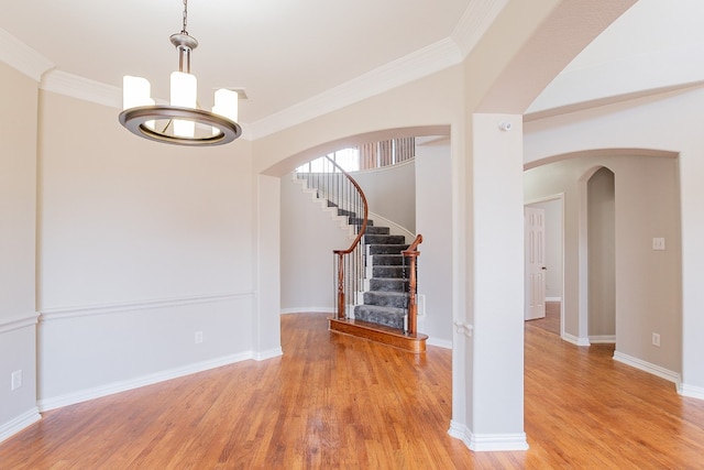 spare room featuring crown molding, light hardwood / wood-style flooring, and an inviting chandelier