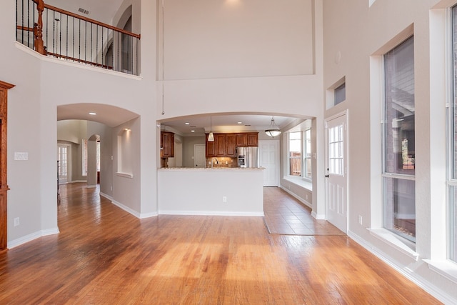 unfurnished living room featuring a high ceiling, sink, and light wood-type flooring