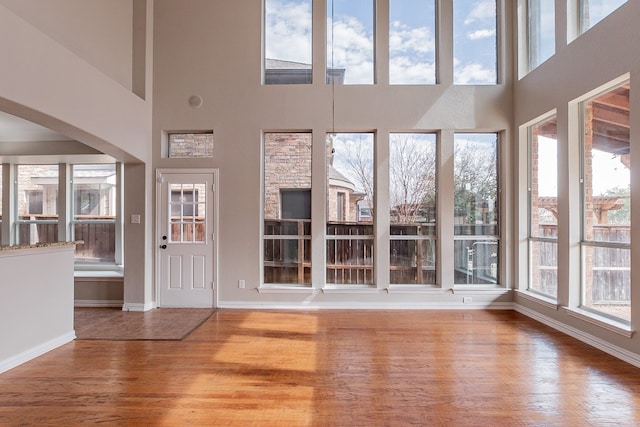 entrance foyer featuring a healthy amount of sunlight, light hardwood / wood-style flooring, and a towering ceiling