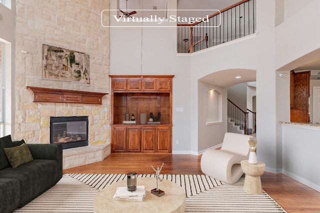 living room featuring a high ceiling, a fireplace, and light hardwood / wood-style flooring