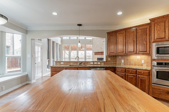 kitchen featuring backsplash, appliances with stainless steel finishes, sink, butcher block counters, and pendant lighting