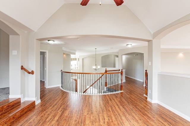 unfurnished room with dark wood-type flooring, ceiling fan with notable chandelier, and vaulted ceiling