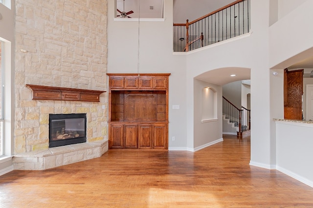 unfurnished living room with light hardwood / wood-style flooring, a fireplace, and a towering ceiling