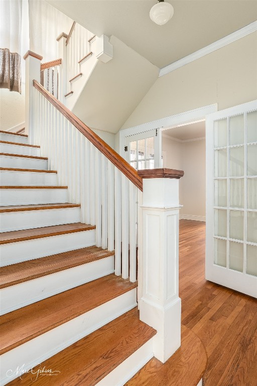 stairway with light hardwood / wood-style floors and ornamental molding