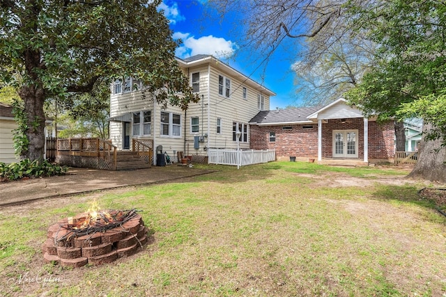 rear view of house featuring an outdoor fire pit, a deck, and a lawn